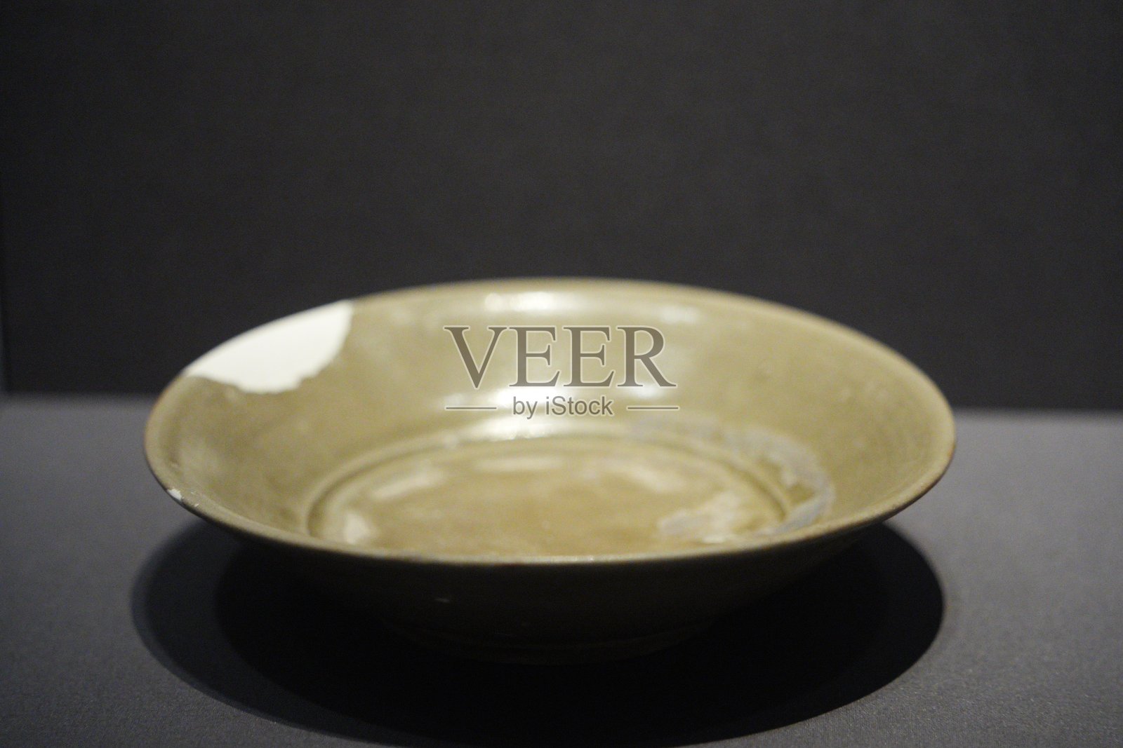 青釉瓷盘静置深色背景展陈照片摄影图片