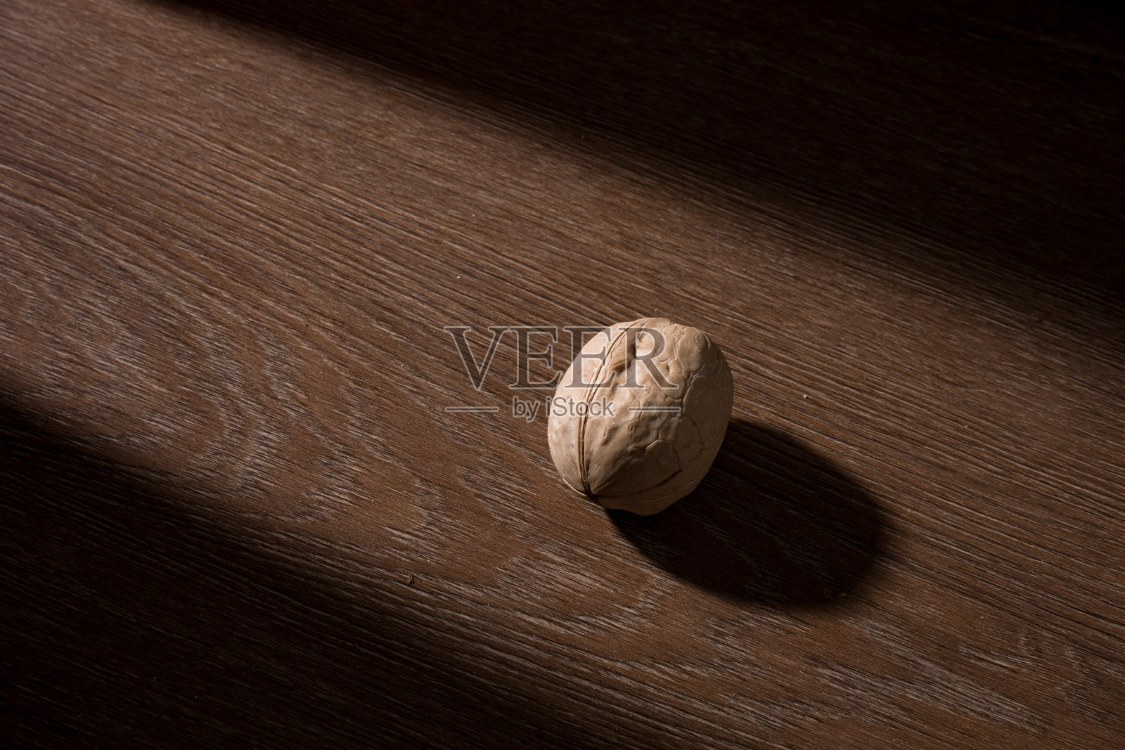 木质桌面单颗核桃光影特写照片摄影图片