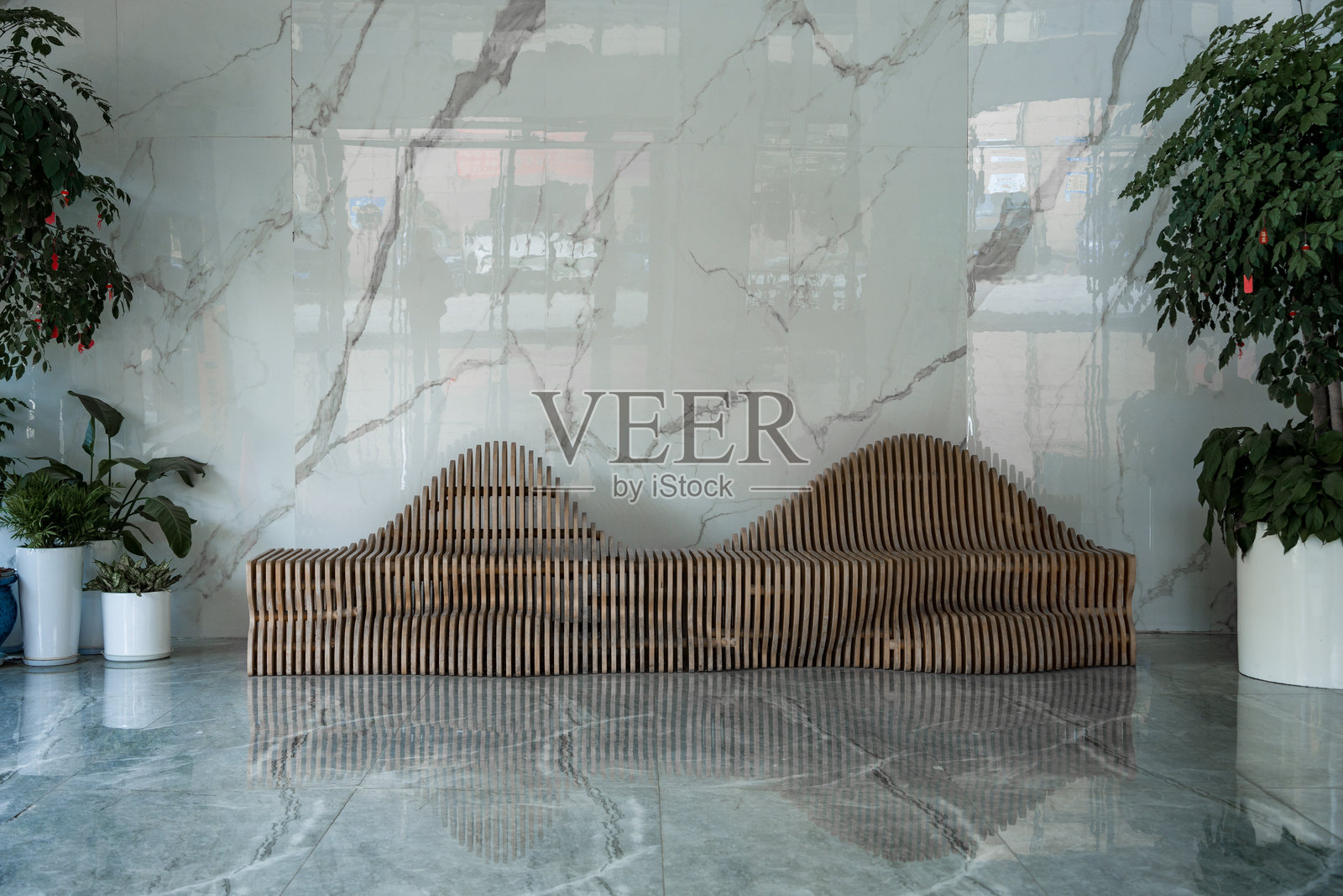 大理石背景前波浪形木条长椅绿植装饰照片摄影图片