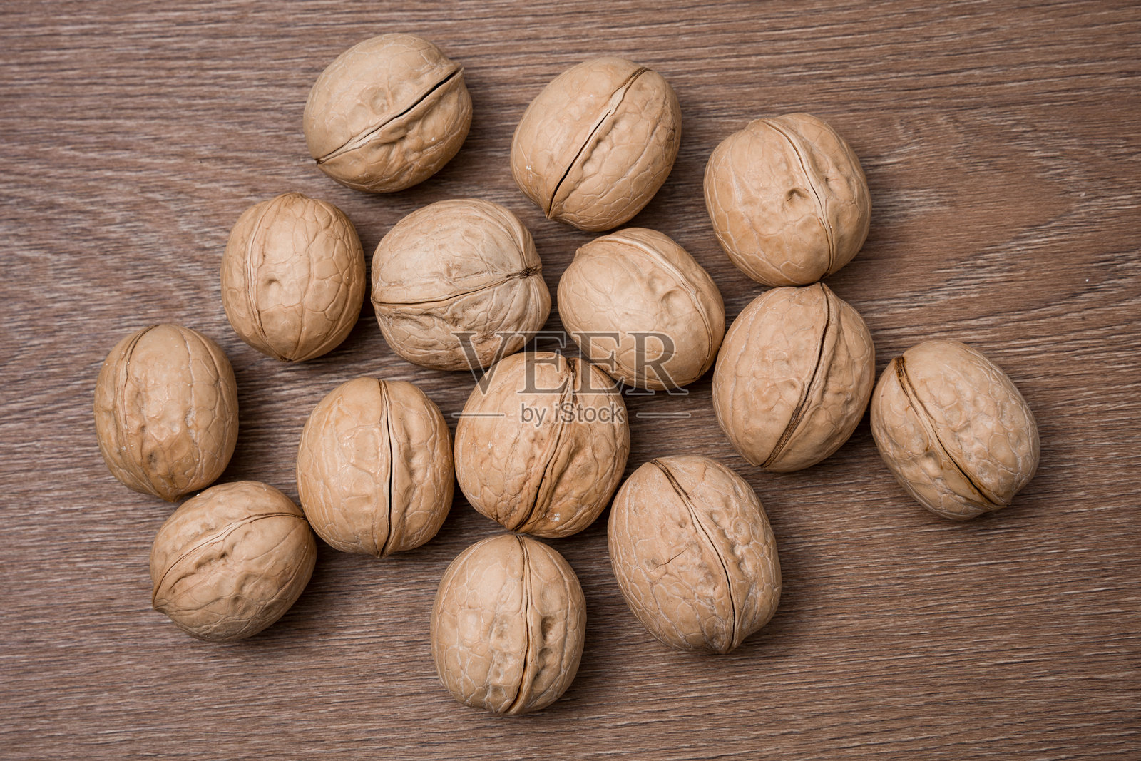 木质桌面上散落的带壳核桃特写照片摄影图片
