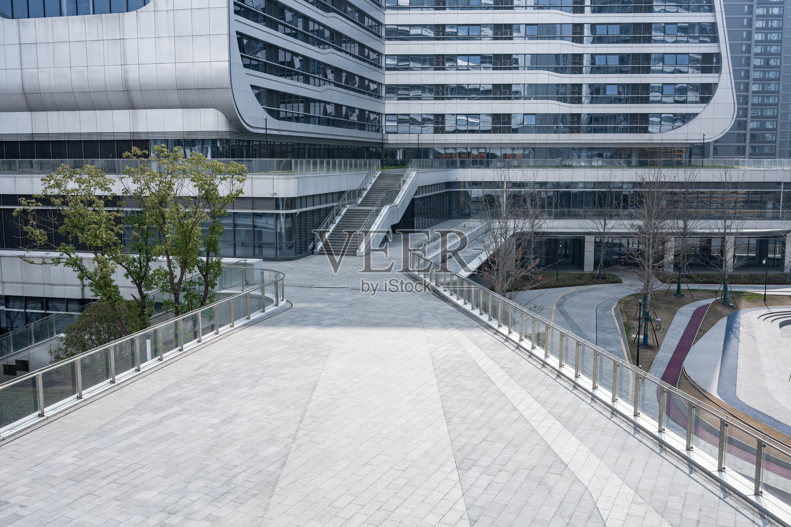 现代建筑群间灰色铺装步道与绿植景观照片摄影图片