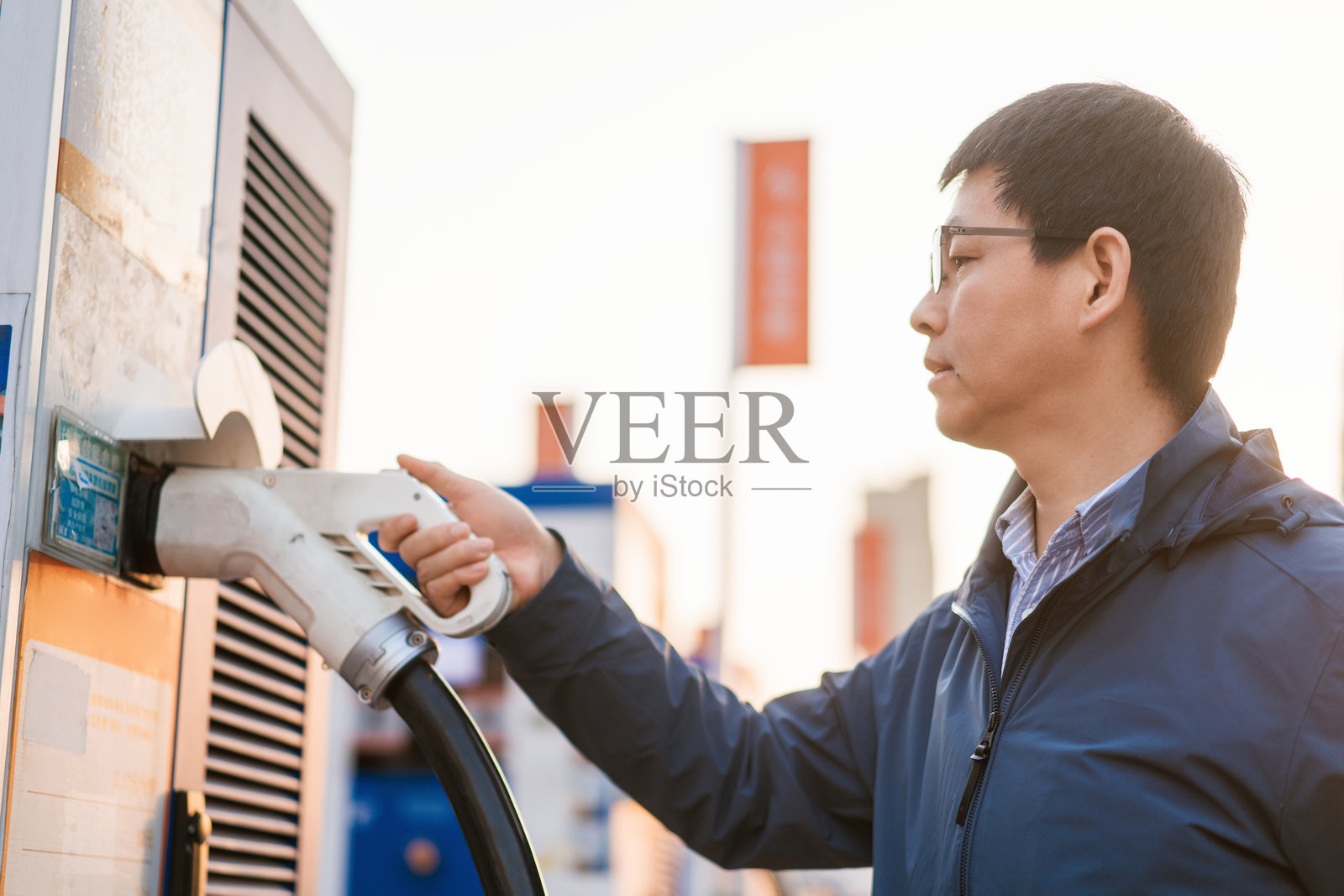 男子正在为电动汽车连接充电枪照片摄影图片