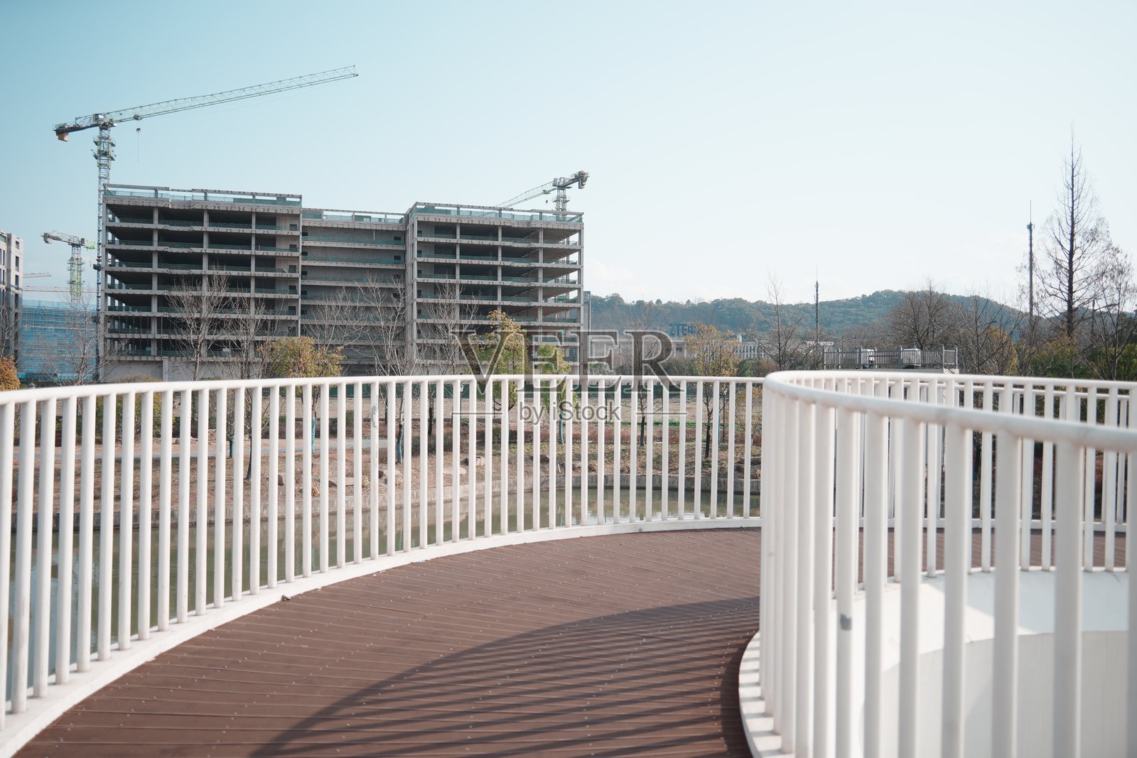 白色弧形步道旁在建高楼与塔吊照片摄影图片