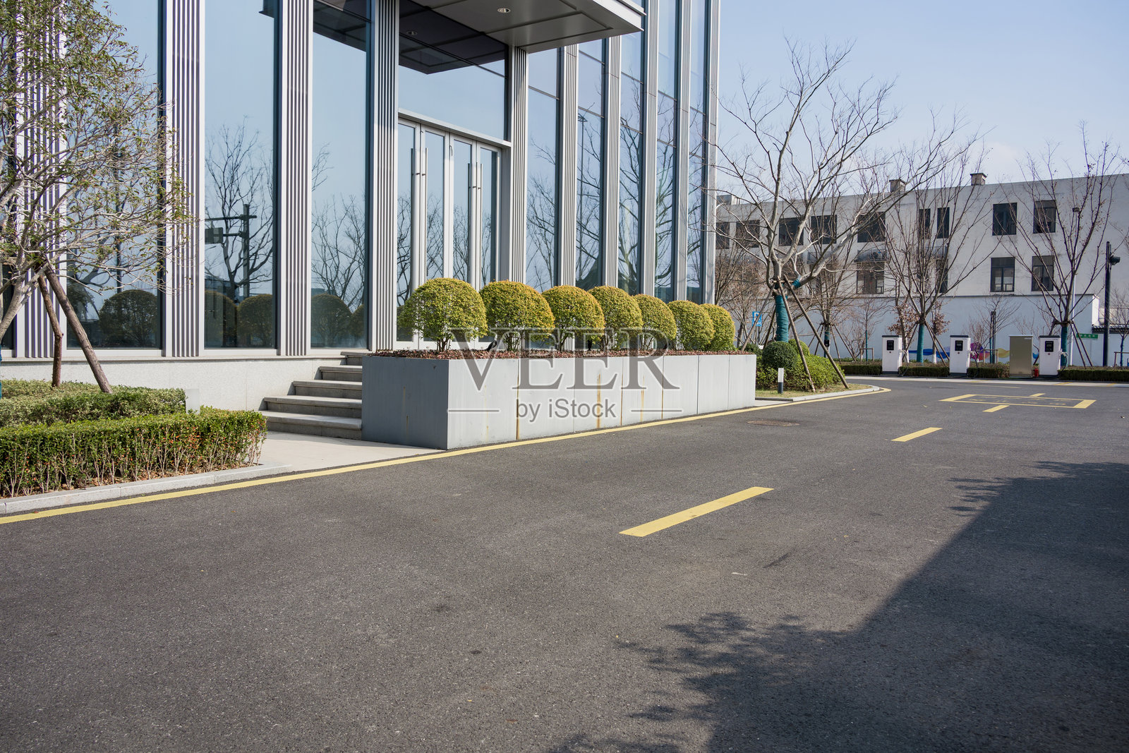 现代办公楼前绿化带与沥青道路照片摄影图片