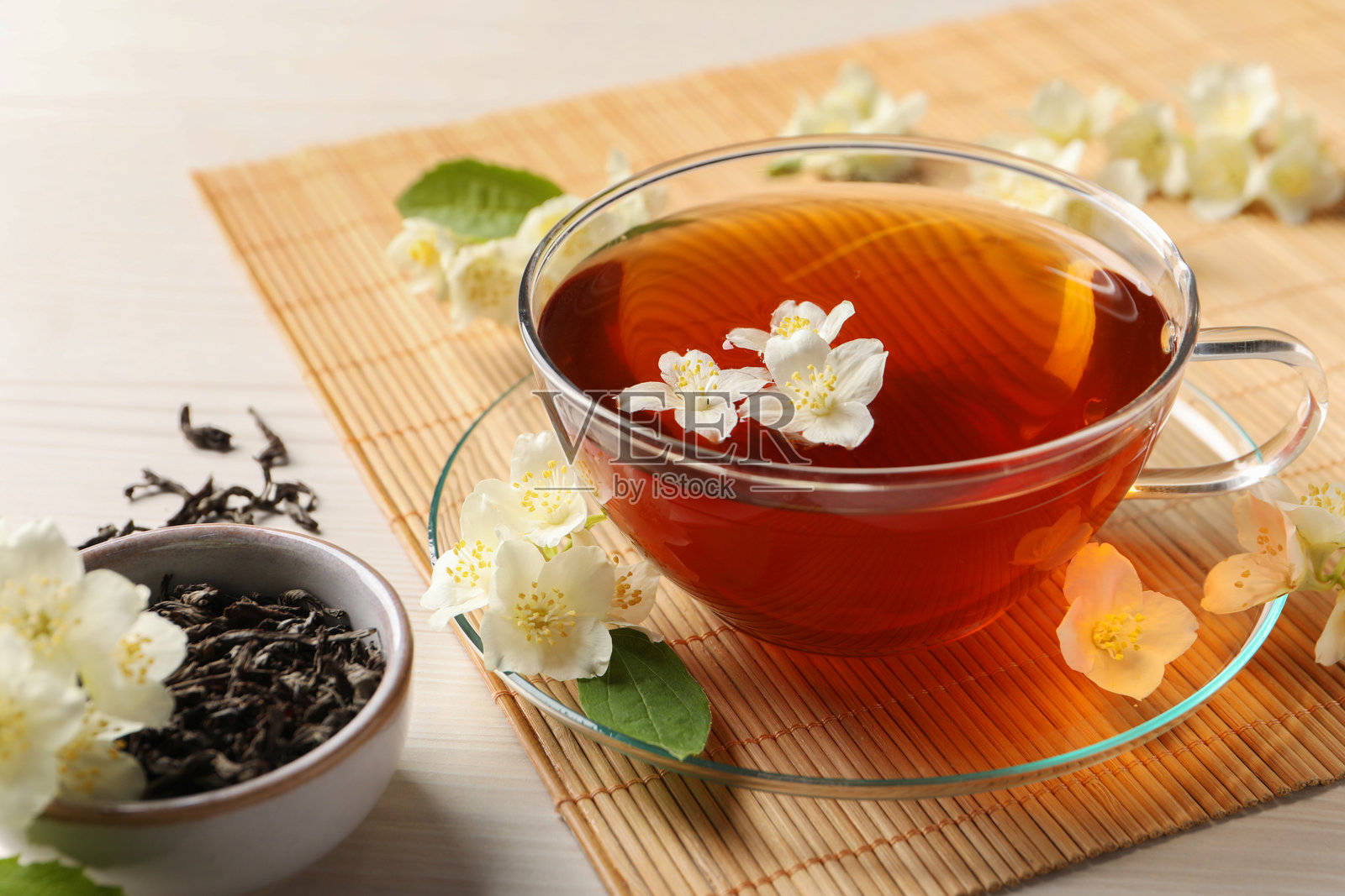热茉莉花茶在杯中，旁边放着花朵，置于白色木桌上照片摄影图片