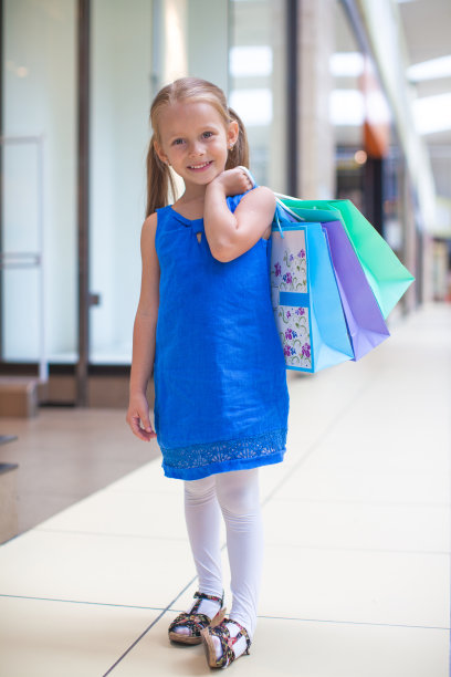 在大型购物中心拿着包裹的时尚小女孩图片下载