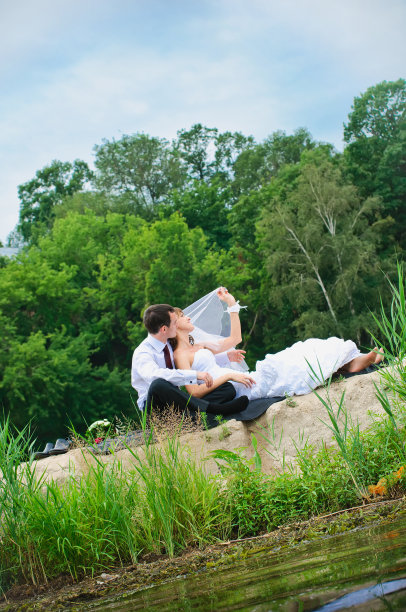 一对恩爱的新婚夫妇坐在海边的沙滩上图片下载