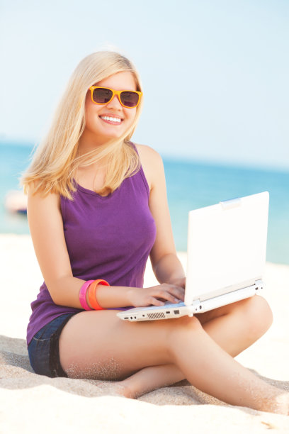 沙滩上一个带着笔记本电脑的金发美女图片下载
