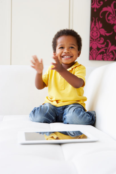 快乐男孩在沙发上玩数字平板电脑图片下载