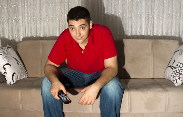 坐在沙发上看电视的年轻人图片下载