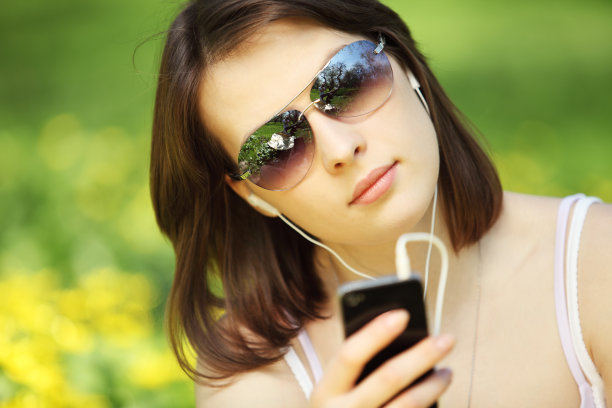 年轻美丽的女子在夏季公园阅读信息的形象图片下载