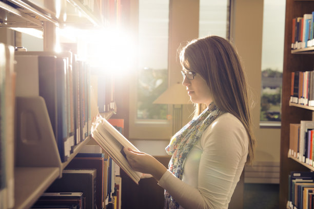 美丽的阳光下，年轻的女孩在图书馆看书图片下载