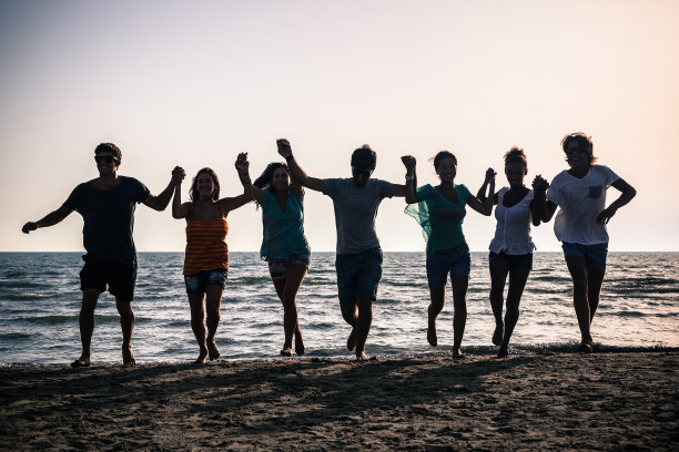 日落时分，一群人在海滩上跑步图片下载