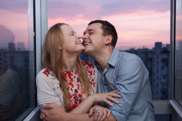 一对年轻夫妇在阳台上拥抱、大笑图片下载