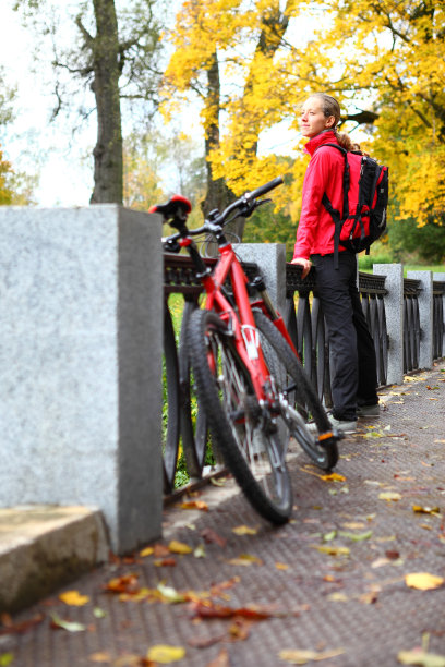 女孩骑着自行车在秋天公园的桥上图片下载