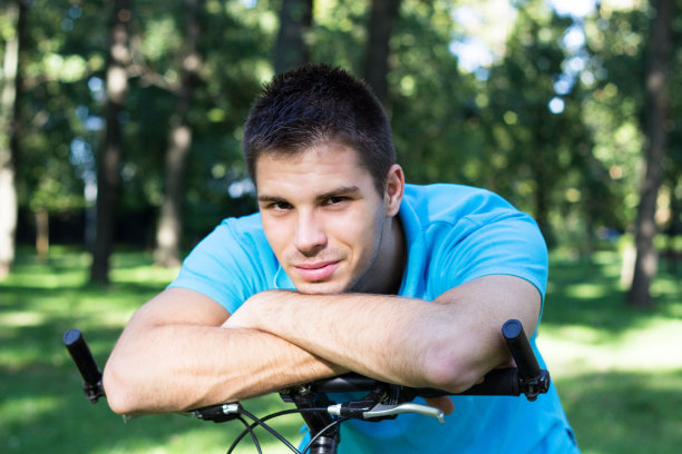 微笑的年轻人靠在自行车上图片下载