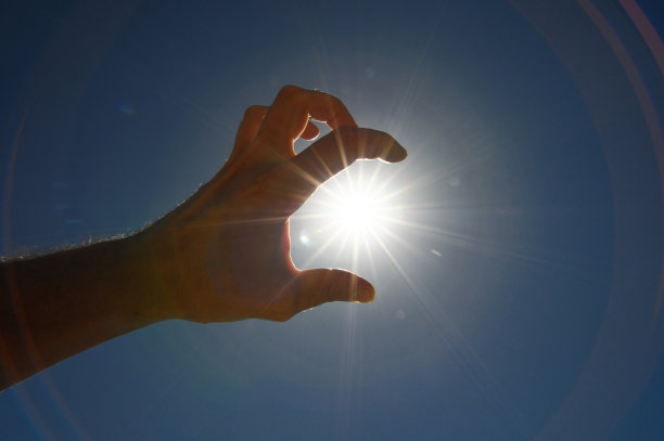 一只手捕捉太阳的星星在一个蓝色的背景图片下载