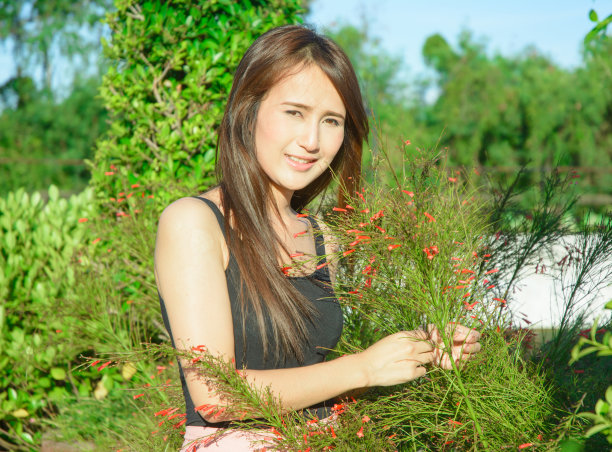 年轻的亚洲女孩微笑着触摸鲜花图片下载