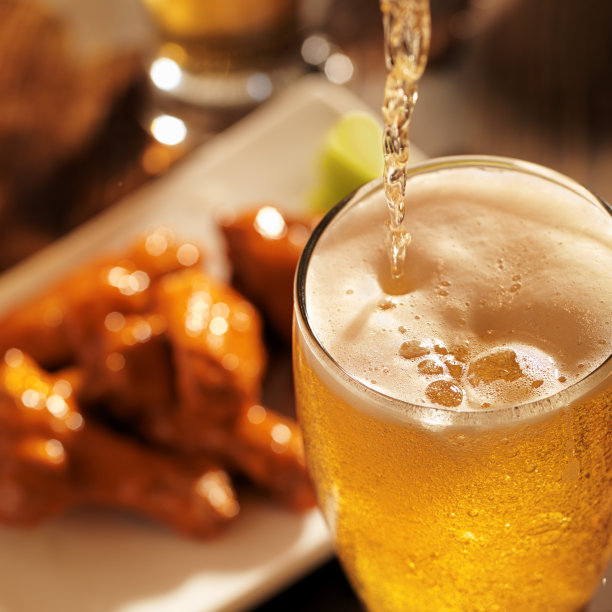 倒着啤酒，背景是鸡翅。图片下载