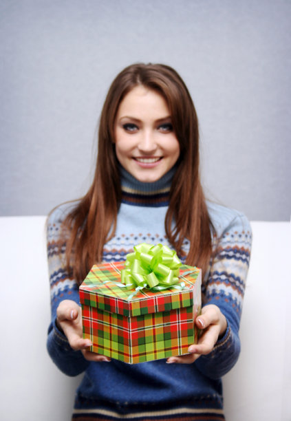 笑容可掬的漂亮女孩赠送包装好的礼物图片下载