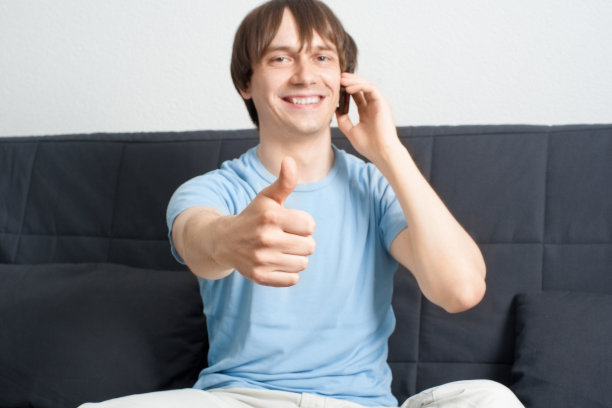 年轻人一边讲电话一边竖起大拇指图片下载