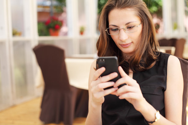 这是一位年轻的女商人在咖啡馆里看她的智能手机图片下载