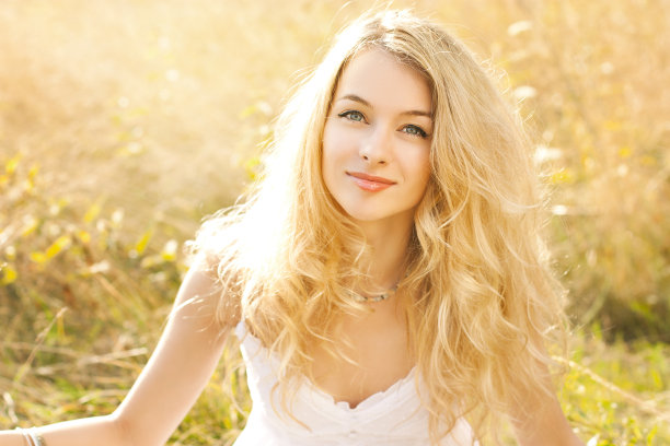 一个美丽的金发女人坐在田野上的肖像图片下载