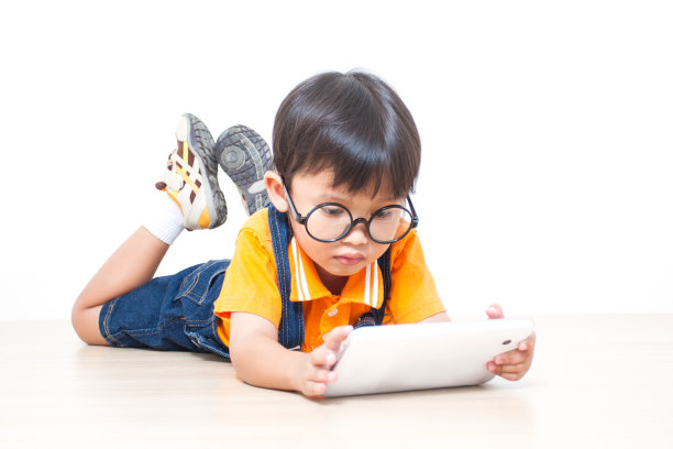 一个戴着眼镜的小男孩在平板电脑上玩图片下载