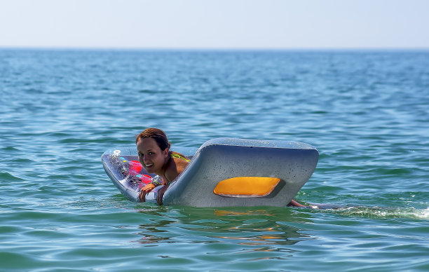 快乐的女孩漂浮在充气床垫上图片下载