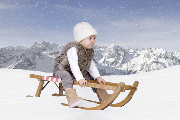 一个蹒跚学步的小孩在雪地里玩雪橇图片下载
