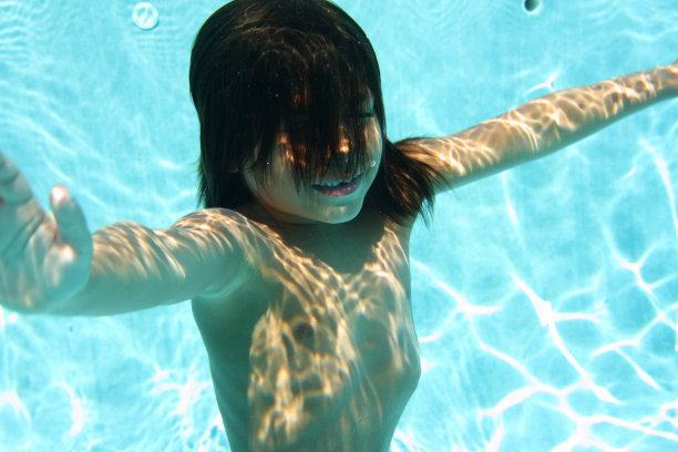 水下男孩在泳池中浮出水面图片下载