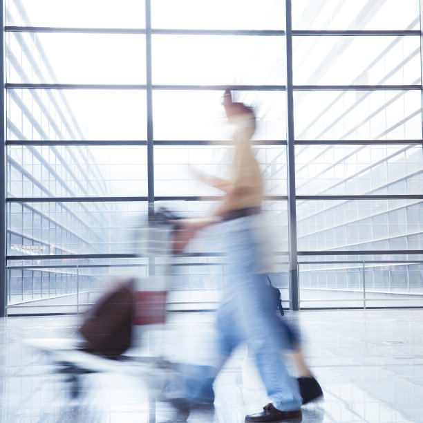 模糊的旅客拖着行李箱在机场走廊上图片下载