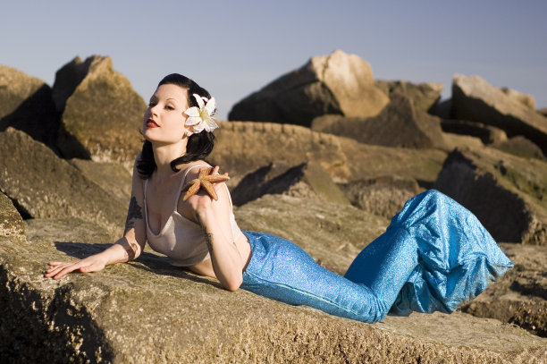 一个手里拿着海星的年轻女子躺在岩石上图片下载