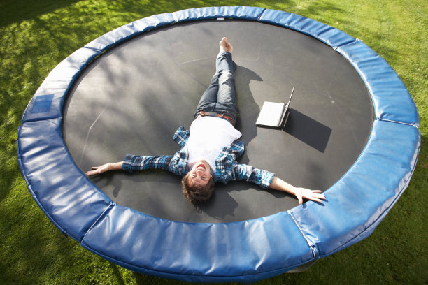 用笔记本电脑在蹦床上休息的年轻人图片下载