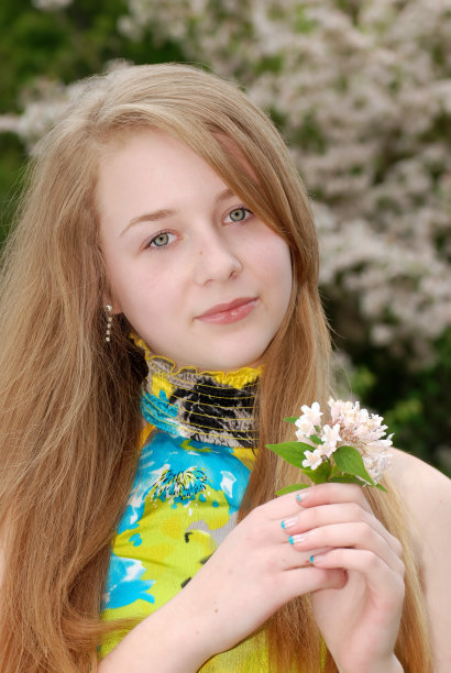 手持鲜花在花园里的年轻少女图片下载