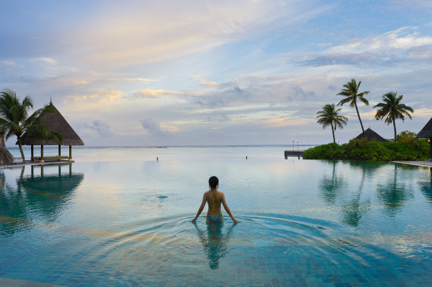在马尔代夫度假胜地的无边泳池里游泳的女孩素材图片