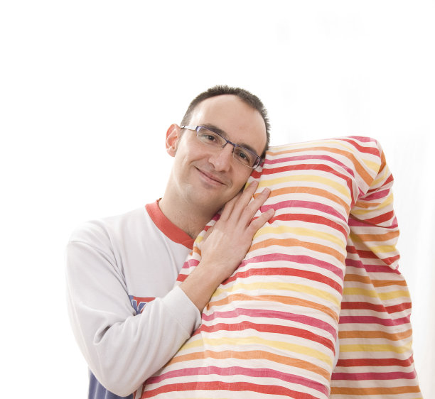 年轻人穿着睡衣，拿着枕头打哈欠图片下载