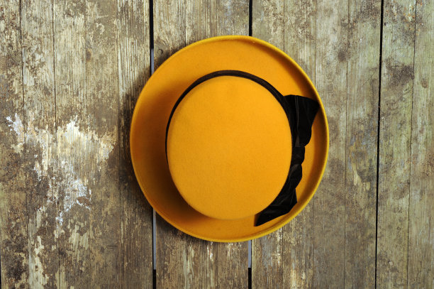 黄帽子挂在破旧的木墙上图片下载