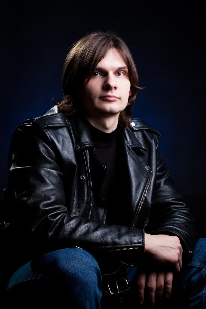 黑色背景下穿着黑色皮夹克的年轻人图片下载
