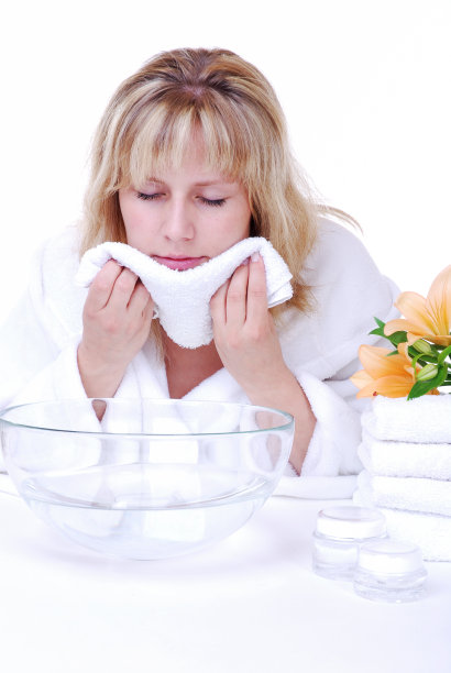 一个女人正在用毛巾和一碗水洗脸图片下载