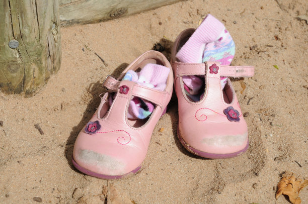 小女孩的粉色皮凉鞋和袜子在沙坑里图片下载