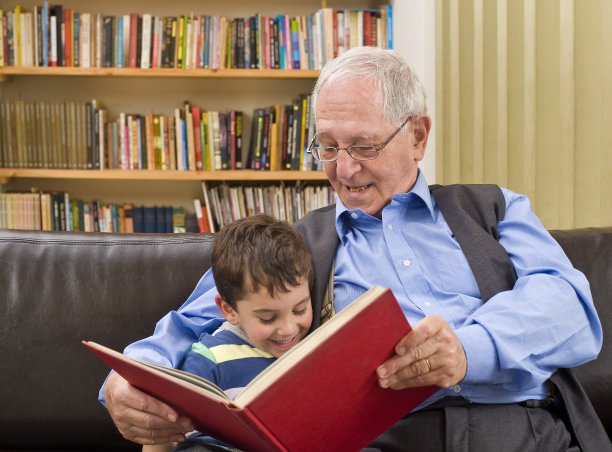 爷爷和孙子在沙发上读故事图片下载