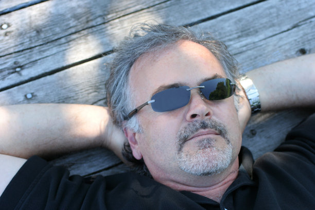 一个成熟的男人躺在码头上。图片下载