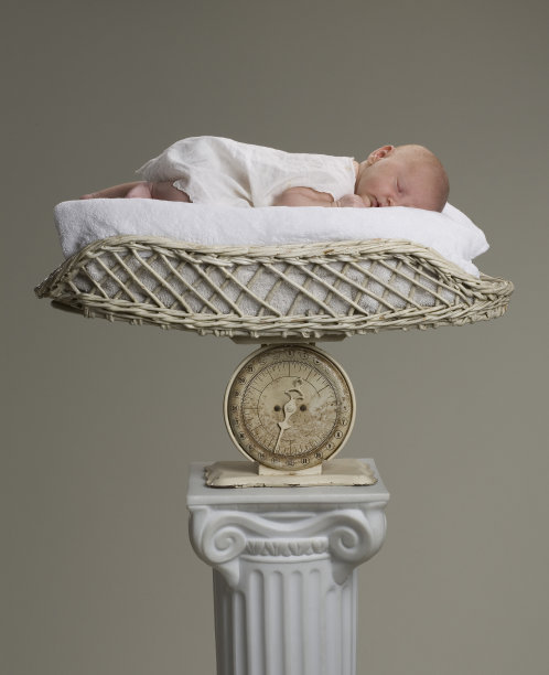 新生婴儿躺在古董秤上图片下载