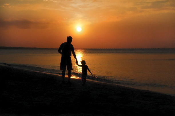 父亲和女儿在海滩上的夕阳下散步图片下载