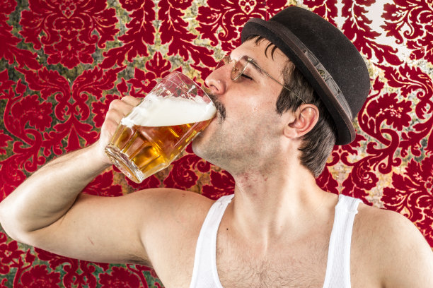 戴着眼镜的黑发白人正在享用大杯啤酒图片下载