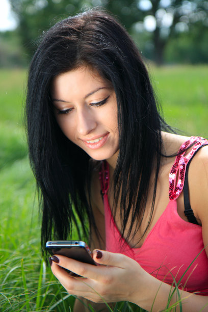 年轻女子看着手机微笑着图片下载