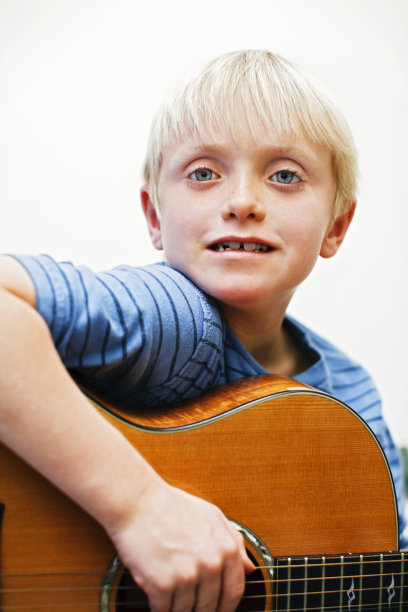 7岁的男孩自信地弹奏着原声吉他图片下载
