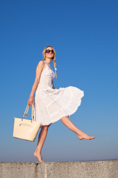 在天空的背景上拿着包的女孩图片下载