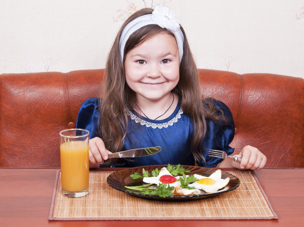 小女孩坐在桌子旁，吃着炒鸡蛋图片下载